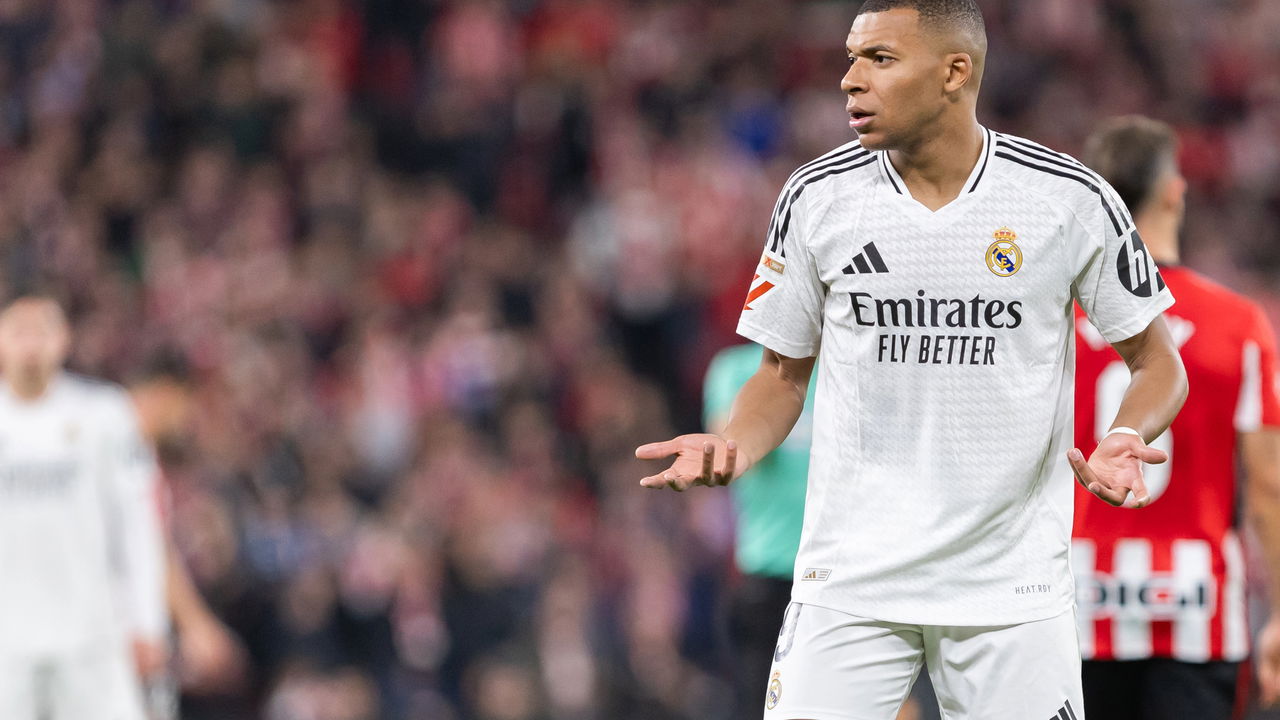 Kylian Mbappé levantando um troféu em meio a uma torcida vibrante